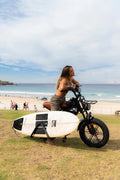 Rider with surfboard on Coogee Bikes Explorer with surf rack at Bondi Beach